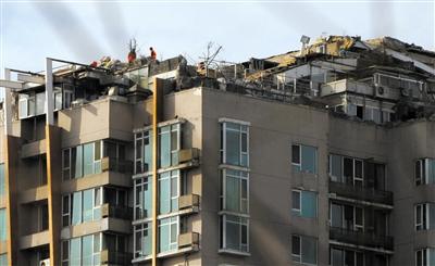 昨日,身穿橘黃色馬甲的工作人員在人濟山莊樓頂拆除違章建筑。新京報記者 吳江 攝 昨日,身穿橘黃色馬甲的工作人員在人濟山莊樓頂拆除違章建筑。新京報記者 吳江 攝