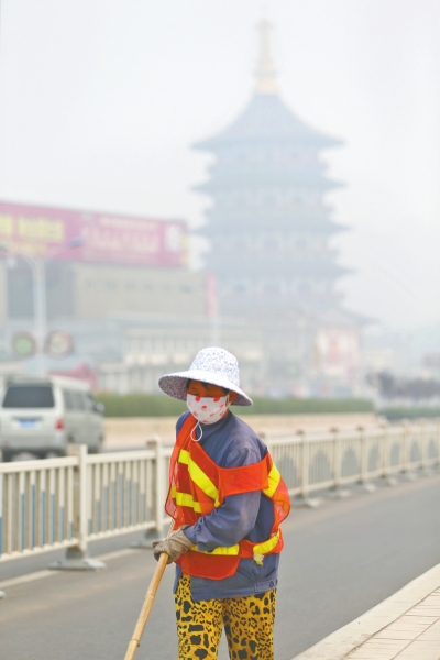 近日，在古都洛陽，環衛工人身后的“天堂”被霧霾籠罩著。