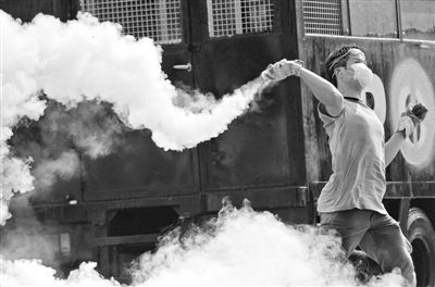 12月2日,泰國曼谷,一名反政府示威者在總理府附近向負責執勤的警察投擲催淚彈。英拉請求示威者不要再試圖占領政府工作部門,不要逼迫政府工作人員選邊站。 12月2日,泰國曼谷,一名反政府示威者在總理府附近向負責執勤的警察投擲催淚彈。英拉請求示威者不要再試圖占領政府工作部門,不要逼迫政府工作人員選邊站。