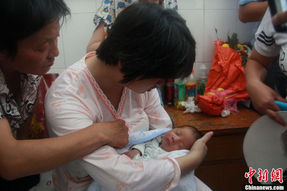 圖為久別重逢，獲救嬰兒母親悉心撫摸愛子。張一辰 攝