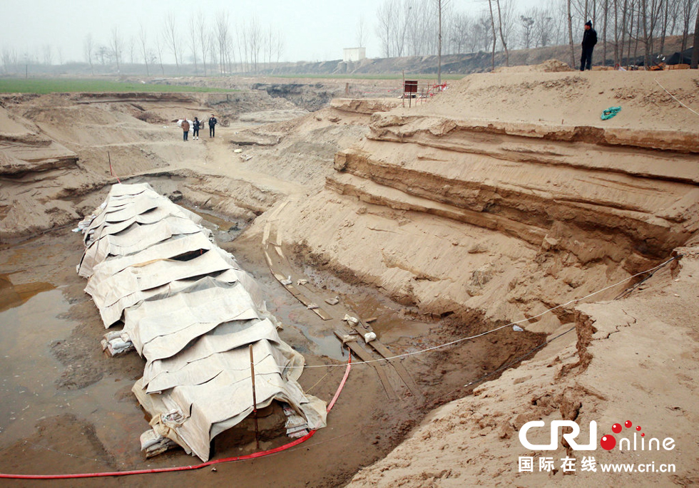 2014年1月6日，河南洛陽古沉船發(fā)掘現(xiàn)場，近日有雨雪天，考古人員給古沉船披上一層“雨衣”。