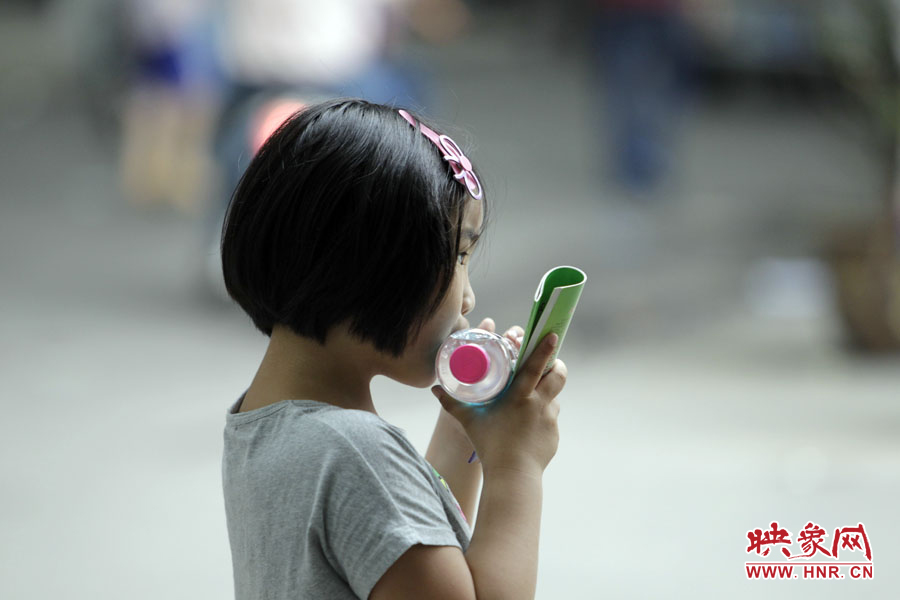 6月7日，鄭州回中考點，一名孩子拿著一瓶礦泉水，等待哥哥走出考場