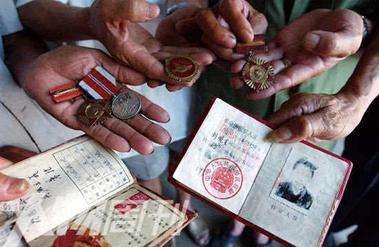 幾位志愿軍老兵展示自己的立功證、傷殘軍人證與勛章