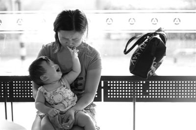 昨日，肯德基京廣中心店門口，姜女士提起跟養父母的關系時落淚，懷中9個月的女兒笑著跟她玩。新京報記者 薛珺 攝