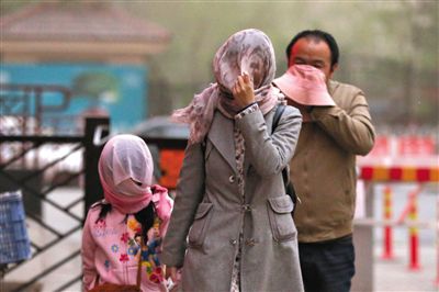 昨日下午，朝陽區(qū)豆各莊，行人將紗巾裹在頭上防沙塵。