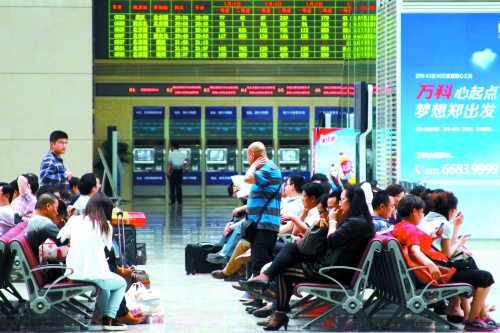 候車大廳溫度很高，一名乘客一手扇風、一手擦汗