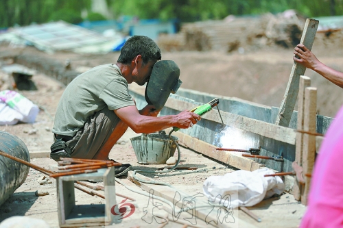 　正午陽(yáng)光下，工地上的焊接工人還在認(rèn)真工作。