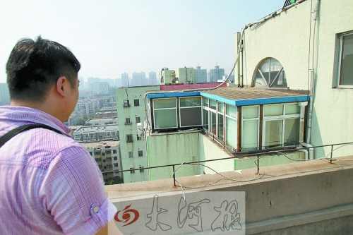 執法人員正在對一高層住宅樓頂層加蓋的違章建筑調查取證