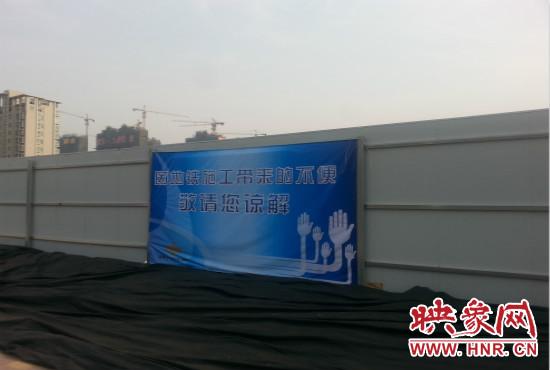 道路南側圍起了白色的圍擋，墻上標示著“因地鐵施工帶來的不便敬請您諒解”的提示牌。