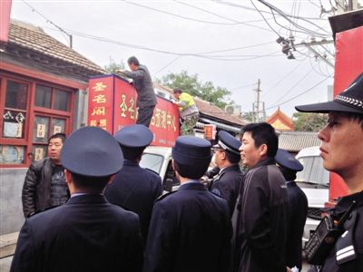昨日下午,東城區(qū)工商、城管、公安等部門,對(duì)雍和宮附近的預(yù)測中心進(jìn)行清理整頓,站在車頂?shù)膬擅と苏鸪患摇邦A(yù)測中心”的招牌。因雍和宮、白云觀等文化景點(diǎn)外聚集大量算命先生,被媒體稱為“算命一條街”。本版攝影/新京報(bào)記者 李寧 攝