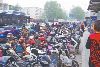 省人民醫(yī)院北門，路邊的公交站牌處停滿非機動車，上、下客只能在快車道上。