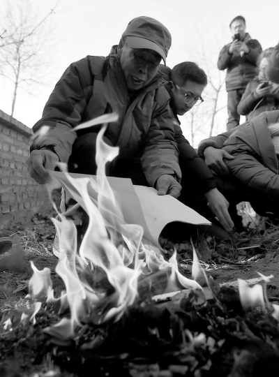 李三仁在兒子墳前焚燒再審無罪判決文書的復印件。新華社發