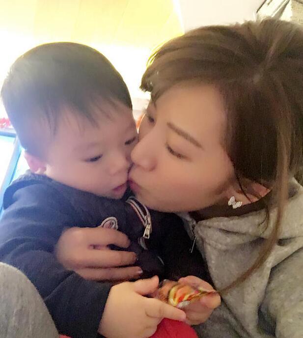 照片中李念狂吻兒子，小寶貝自顧自地玩著。