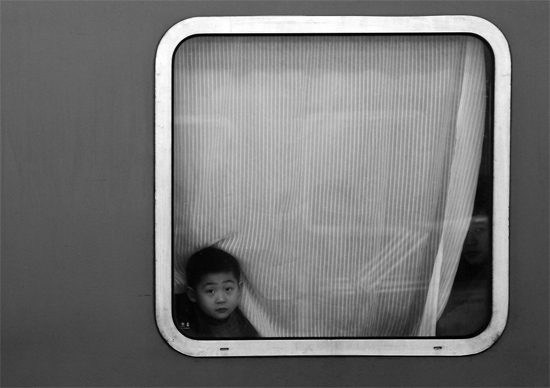 一個孩子把頭伸向窗外，他想再看送別的親人一眼