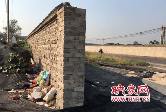 一墻之隔，一邊是道路，一邊是垃圾和荒草，市民質疑其為遮羞墻。