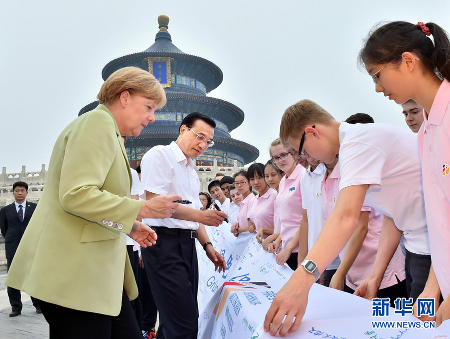 李克強同默克爾在紀念橫幅上簽名。 李克強同默克爾在紀念橫幅上簽名。