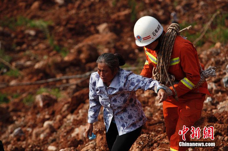 一位消防戰士將一位失去親人的老人扶離滑坡點。