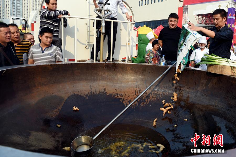 工作人員向大鍋內(nèi)加入油和姜等烹飪調(diào)料。 圖片來源：CFP視覺中國