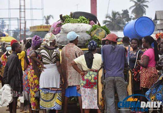 當地時間2014年8月14日，利比里亞蒙羅維亞，市場里的商人們圍著一輛汽車。