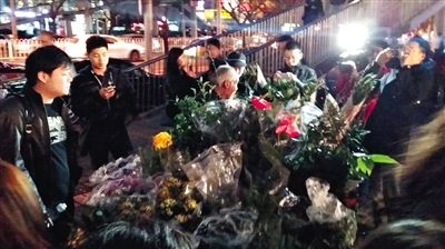 昨晚7時許，三里屯太古里西邊附近一過街天橋旁邊，聞訊而至的網友圍住了賣花老人，爭相買花。 網友“行者橙子”供圖