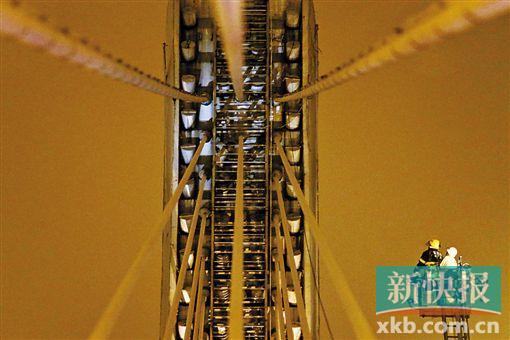 截至今日零時(shí)，男子仍未有下橋舉動(dòng)。圖為公安和消防人員乘消防云梯在高空上和男子交談。